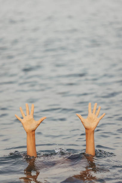 istock Unrecognizable woman hands waving for help, drowning into the sea 1387520437
