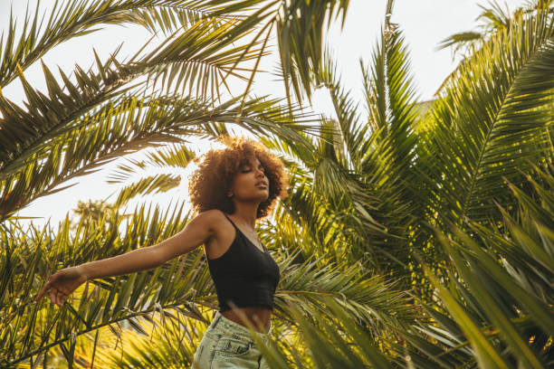 istock Pretty young afro woman among palm trees 1387520661