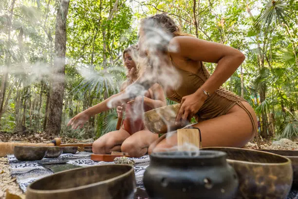 They sit on a Mexican blanket in the jungle preparing for a music therapy and shamanic ceremony.