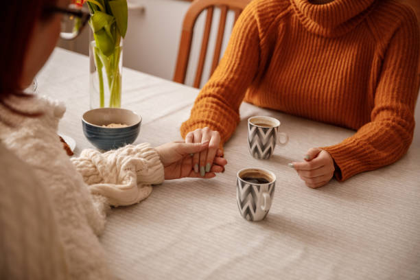 istock Mother and daughter holding hands while chatting and having coffee 1387524481