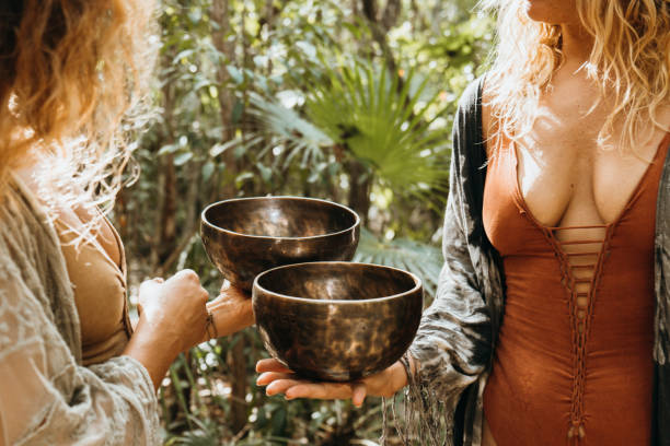 istock Young women doing meditation using a Tibetan singing bowl during the sunrise in a rainforest landscape 1387524821