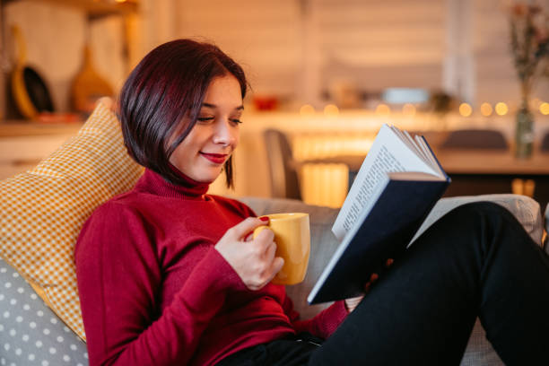 istock Woman lying on sofa and reading book 1387524833