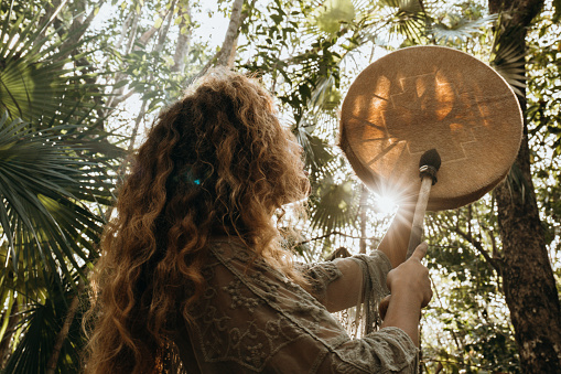 One multiracial woman practicing sound healing ceremony in the rainforest