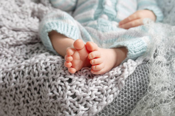 petit pied de nouveau-né. pieds doux de chéri de nouveau-né contre une couverture beige. pieds de chéri avec des orteils recroquevillés vers le haut - un seul bébé fille photos et images de collection