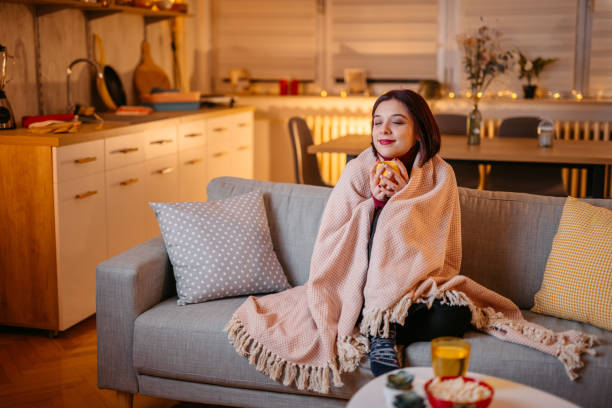 istock Beautiful woman drinking hot tea wrapped in blanket 1387524984