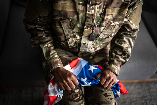 Female soldier hands' holding the American flag at home