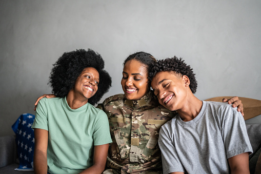 Soldier mother embracing son and daughter at home