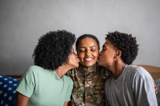 Son and daughter kissing soldier mother at home Son and daughter kissing soldier mother at home mom and sister stock pictures, royalty-free photos & images