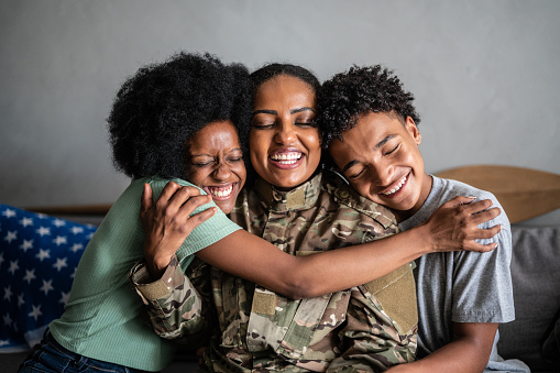 Madre soldado abrazando a hijo e hija en casa photo