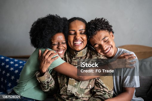 istock Soldier mother embracing son and daughter at home 1387528321
