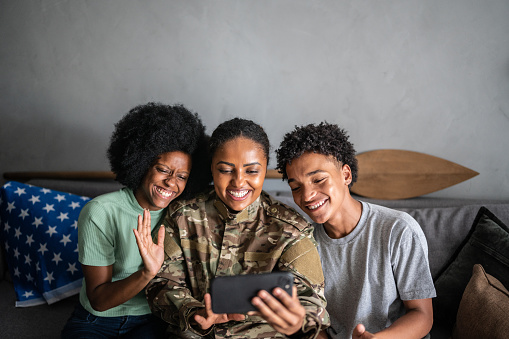Soldier mother with daughter and son on a video call on the mobile phone at home