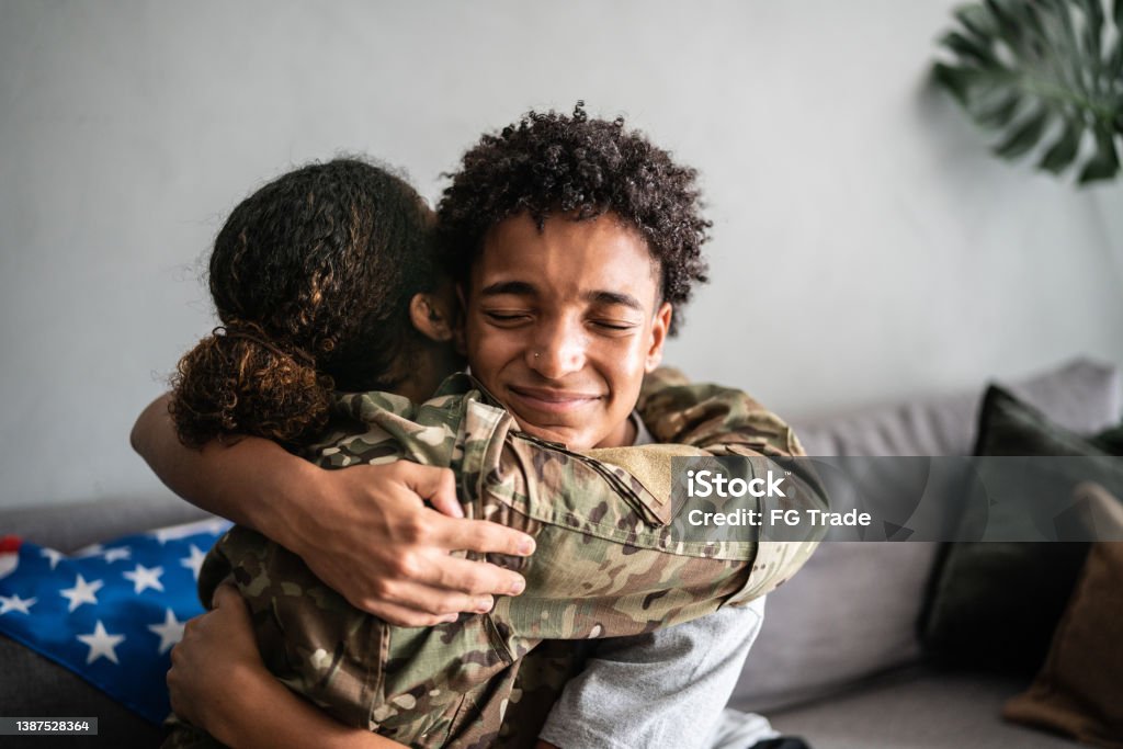 Soldier mother and son hugging each other at home Teenager Stock Photo