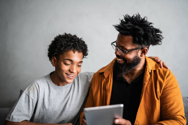 Happy father and son using digital tablet at home Happy father and son using digital tablet at home candid bonding connection togetherness stock pictures, royalty-free photos & images