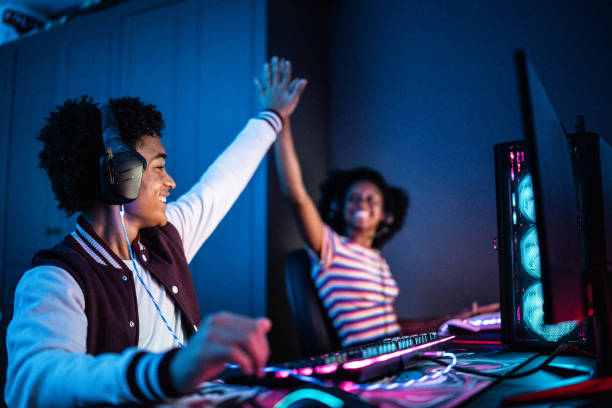 Friends doing a high five while playing on the computer at home Friends doing a high five while playing on the computer at home video game stock pictures, royalty-free photos & images