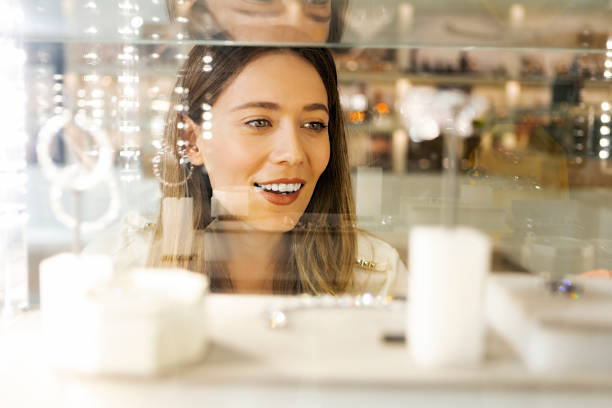 kobieta patrząca na biżuterię w sklepie - earring jewelry women smiling zdjęcia i obrazy z banku zdjęć