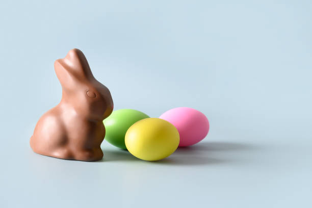 istock Easter pink egg and chocolate bunny in spring composition on blue. 1387530463