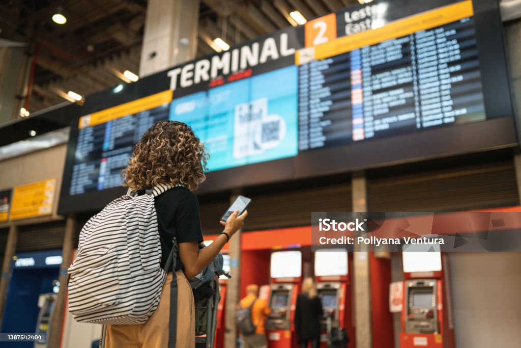 Tourist looking at arrivals and departures table Woman, Back, Cellphone, Bag, Airport, Control Panel Airport Stock Photo