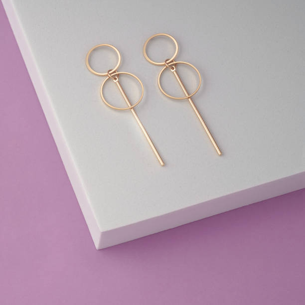 istock Geometric modern earrings pair on white podium with purple background 1387548549
