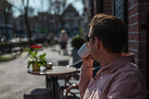 Smiling young woman having a cup of coffee at restaurant. Happy female enjoying a coffee at a outdoor cafe.