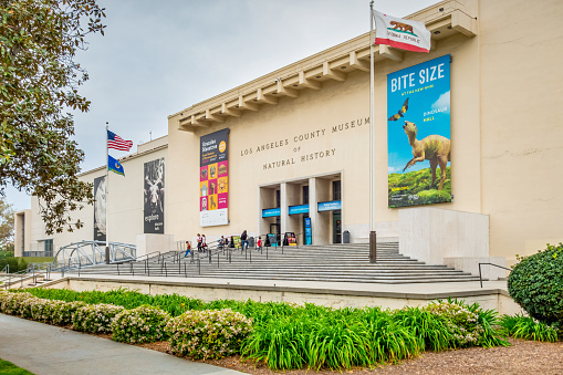People exit the Natural History Museum of Los Angeles County in Los Angeles, California, USA on a cloudy day.