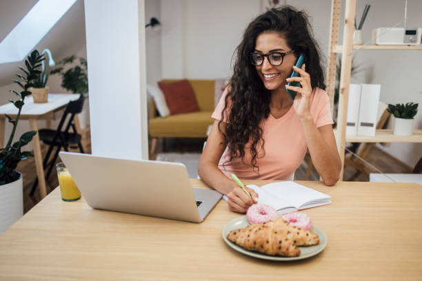 istock Young woman telephoning while working from home 1387557204