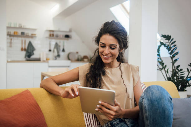 portrait of a happy young woman using tablet at home - using tablet imagens e fotografias de stock