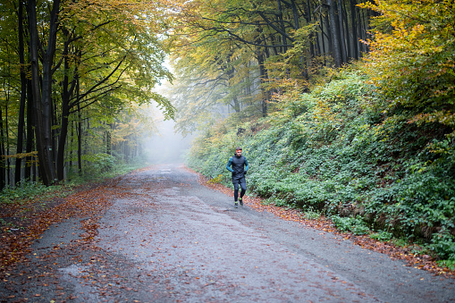 Determined athletic man running through misty autumn nature