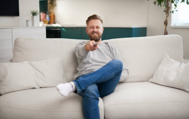 istock Happy man watching TV on sofa 1387557499