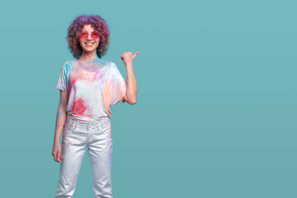 istock Cheerful woman with Holi colors pointing aside 1387557545