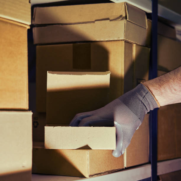 istock A man in gloves steals goods from a box in a warehouse. Problems with theft and security in the office 1387558131