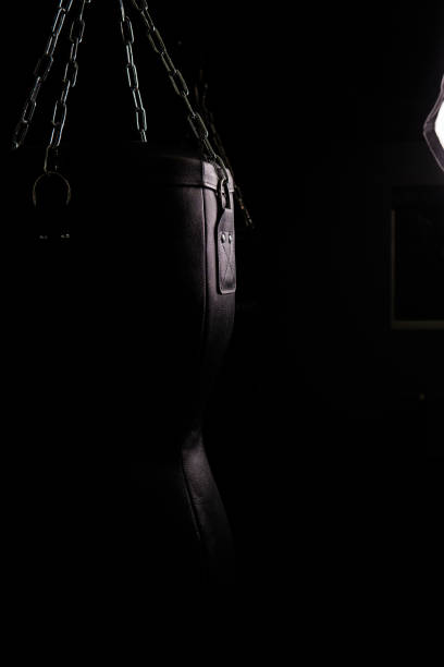 On black background opy space bag black punching boxing background leather, from knockout equipment for gym for aggression impact, body beat. Kickboxing bags winning, stone black