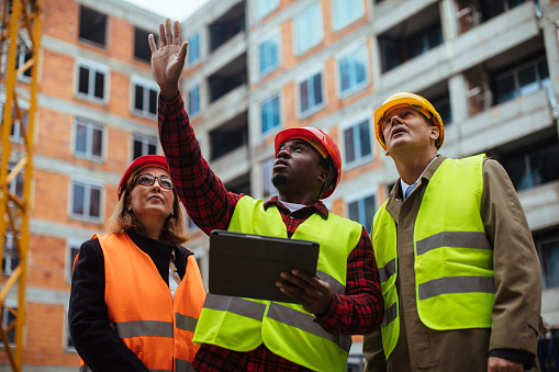 Three colleagues visiting a construction site while working on a digital tablet