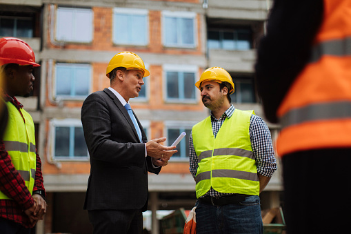 Construction worker and his colleagues meeting a business investor at a construction site