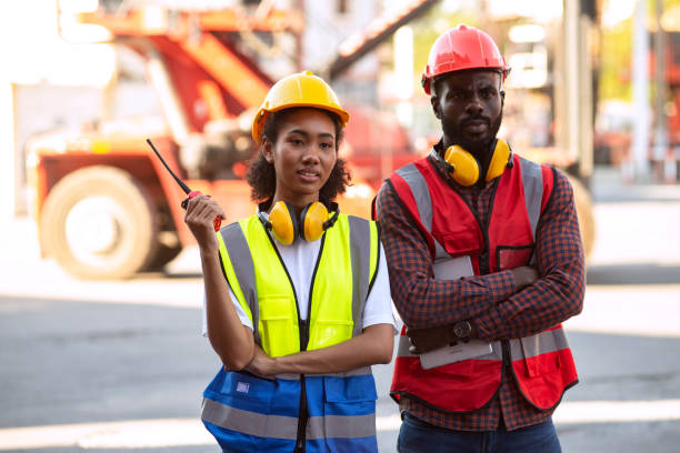 istock Serious two African american male and female worker checking control loading freight containers from Cargo freight ship for import export. 1387571594