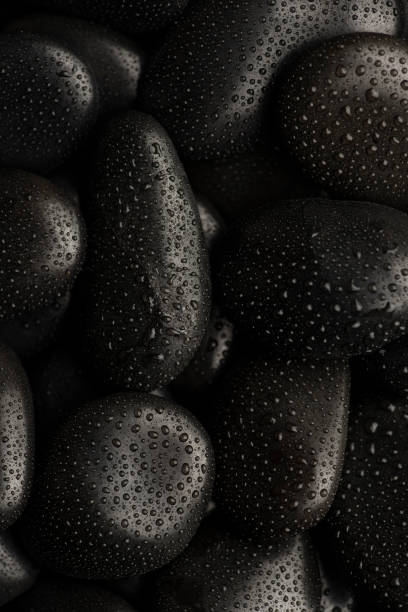 istock Black natural stones covered in rain drops showing textures and patterns formed 1387578478