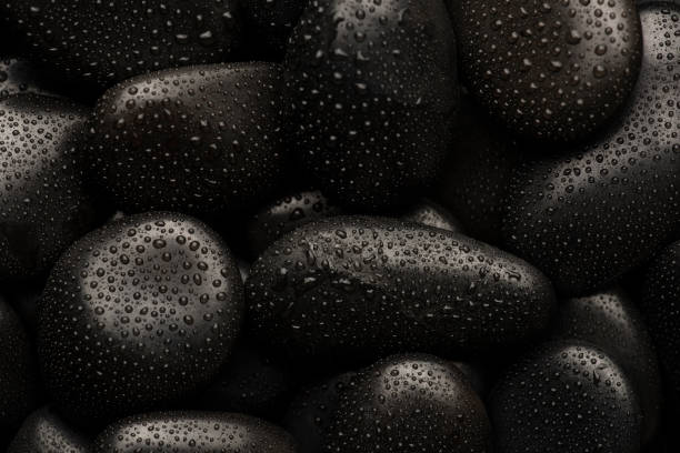 istock Black natural stones covered in rain drops showing textures and patterns formed 1387578492
