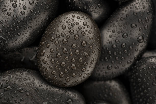 istock Black natural stones covered in rain drops showing textures and patterns formed 1387578493