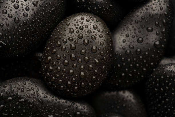 istock Black natural stones covered in rain drops showing textures and patterns formed 1387578495
