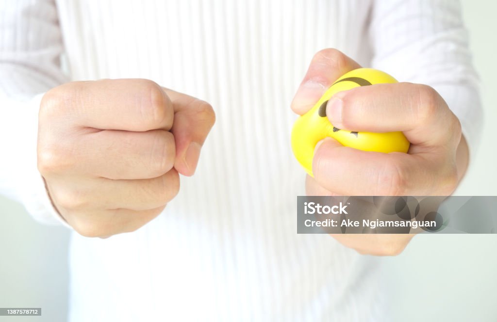Hands of man with a gentle personality He exhibits stressful behavior from work, and he squeezes the yellow ball expressing emotion, anger, displeasure. Medical concepts and emotional regulation Borderline Bar & Grill Stock Photo