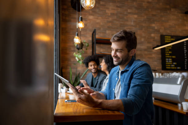 istock Happy man working online at a cafe while drinking a cup of coffee 1387578810