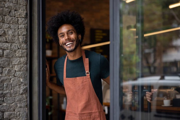 istock Happy waiter opening the door at a restaurant 1387578821