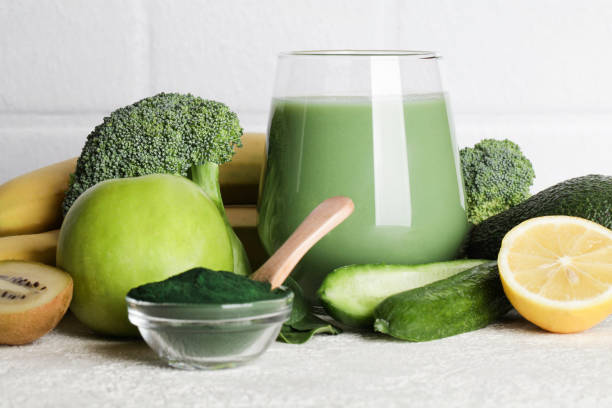 green smoothie in glass, spirulina powder, vegetables and fruits on white ceramic tile background. healthy, raw, vegan diet concept. - chlorella spirulina bacterium algae nutritional supplement imagens e fotografias de stock