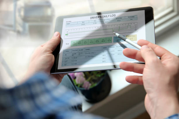 Truck driver checking electronic logbooks on a tablet stock photo