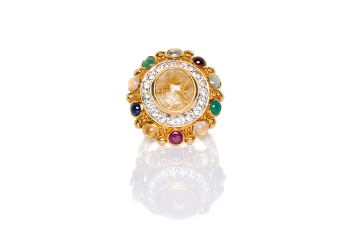 Golden Rutilated Quartz and diamonds with nine gemstones ring on white background with reflection. Collection of natural gemstones accessories. Studio shot