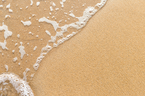 Closeup sandy beach background, fine sand with white wave, nature background, summer outdoor day light