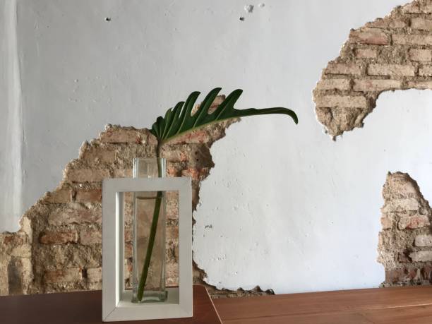 istock Green leaf in stylish vase with antique wall 1387593210