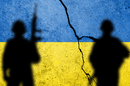 Bandera de Ucrania pintada en un muro de hormigón con soldados photo