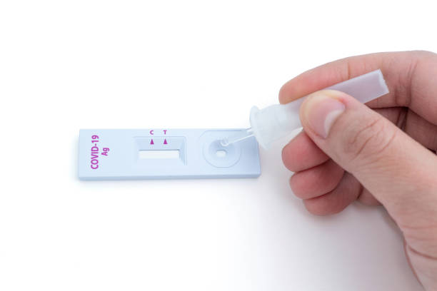 istock Hand squeezing a tube containing a sample of secretions onto a coronavirus testing device 1387603498