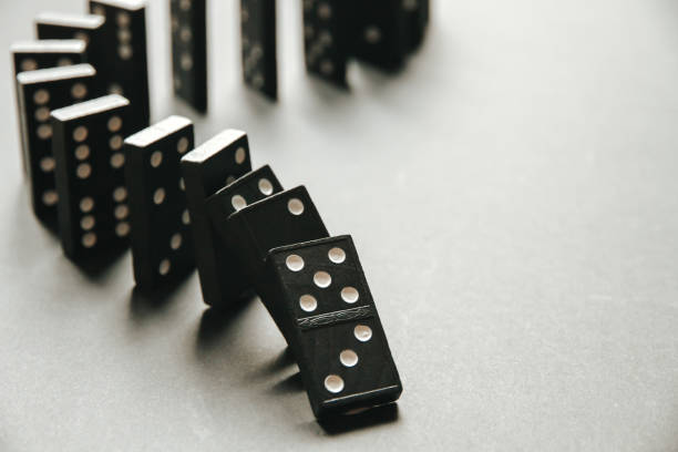 istock Black dominoes chain on white table background 1387604385