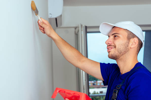 istock Young workman is painting  the wall with paintbrush 1387605403